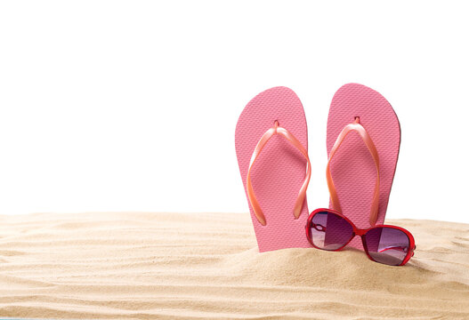 pink female flip flops and sunglasses on a beach sand, isolated on a white background.