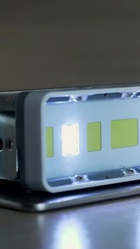 Vertical video: Approaching fingertip pressing LED module on bench, testing left chip brightness