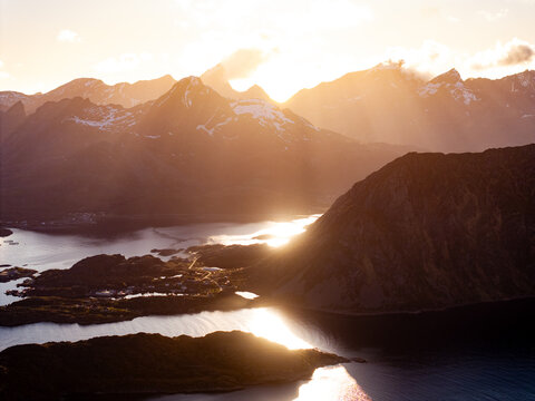 Golden sunset over dramatic mountain fjord with reflective water