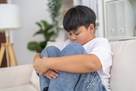 Bullying awareness, sad asian boy sitting alone hugging knees, child mental health, psychological trauma, emotional distress, depression symptom, social isolation, school violence and silent victim