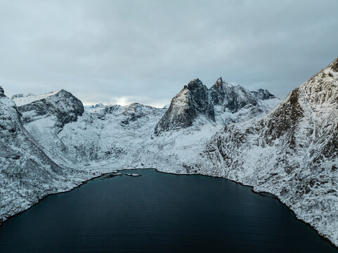 Snowy mountain range surrounding a dark alpine lake