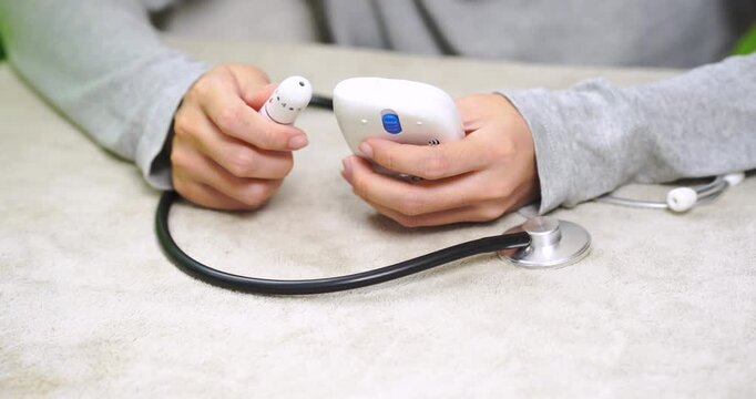 Close-up of a person holding a fingertip pulse oximeter during a home health check. Measuring blood oxygen saturation and pulse rate for self monitoring, home healthcare, and preventive wellness.