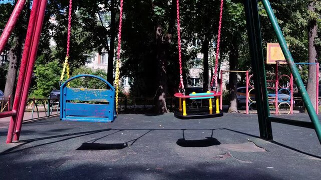 Playground swings standing empty in city park, outdoor activity zone, childhood fun and recreation concept.