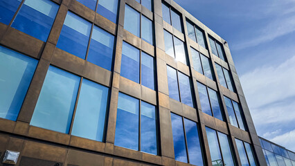 Obraz premium Building with large windows reflecting the sky in a city setting during daytime