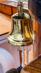Ship bell hangs on a sailing vessel in a sunny harbor © Creative house