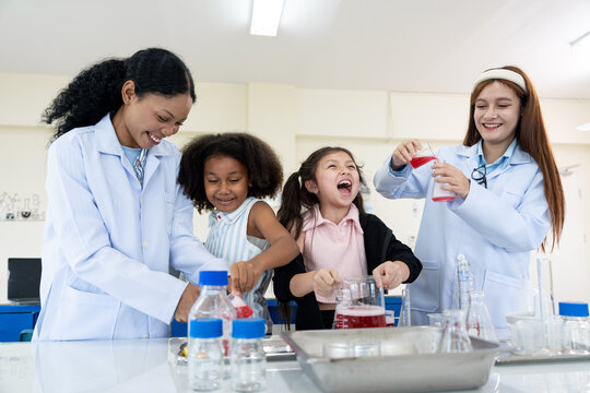 Very two female teachers and two young girls conducting a science experiment in a laboratory