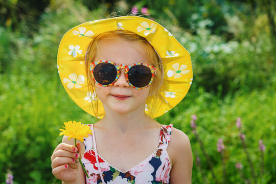 Little girl with daisy, on green grass in a summer park. A gift for the parents.