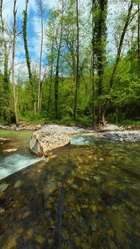 Large stone rests in the stream's path. Gradac River, Serbia. Vertical