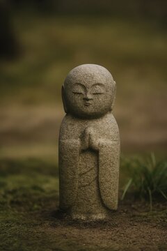 Small stone jizo statue standing peacefully in a traditional zen garden setting