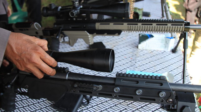 A close up view of precision rifles equipped with optical scopes during a firearms display, highlighting advanced shooting equipment, tactical technology, and marksmanship training.