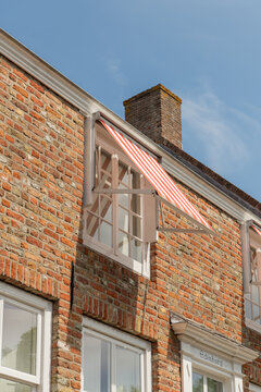Middelburg, Netherlands. Traditional Dutch brick house facade with striped awning and chimney under clear blue sky