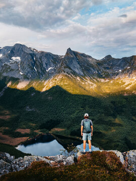 Man traveler standing alone on the mountain cliff edge travel in Norway climbing solo adventure summer vacations tour outdoors, tourist hiker with backpack enjoying views freedom harmony with nature