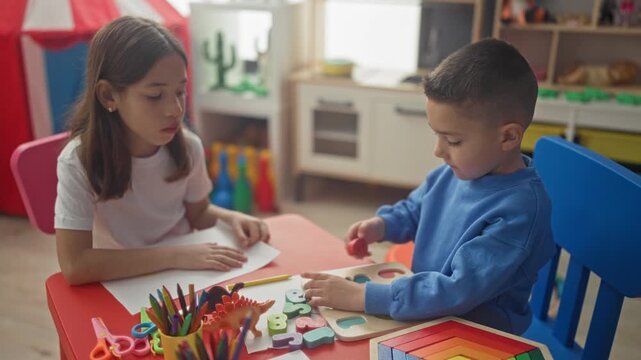 Girl and boy placing wooden number puzzle pieces on a red table in a playroom inside a building; concentration.