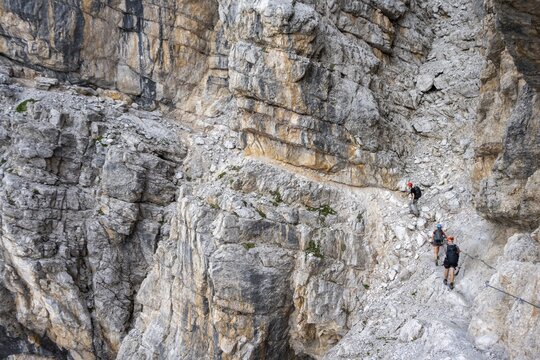 Three hikers on the Via Ferrate Benini via ferrata on a cliff, Brenta Mountains, Parco Naturale Brenta-Adamello, Trentino, Italy