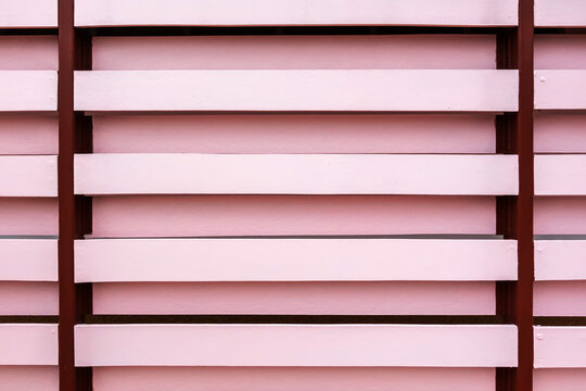 Pink wooden louver fence texture background with brown metal frame. Modern architectural privacy screen made of pink horizontal artificial wood slats installed on dark brown steel frame structure.
