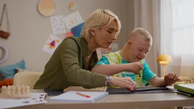 Caucasian mother guiding Caucasian boy with Down syndrome during educational bead activity. Footage representing inclusive learning and special needs support services