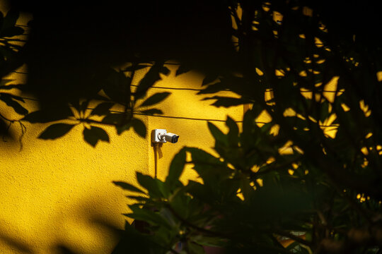 Surveillance Camera on Yellow Wall with Shadows