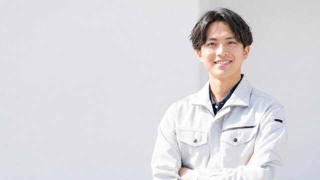 笑顔で腕を組む若い日本人男性作業員のポートレートとコピースペース