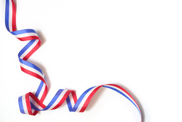 Fototapeta premium French flag colored ribbon twisted on white background in a design with copy space. Concept: celebration of national holidays or traditional festivals
