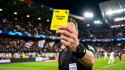 Close up of a soccer referee hand holding up a yellow card in a stadium © Rifqi