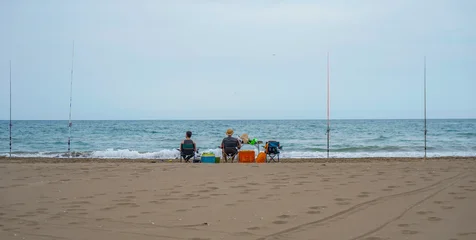 Two people fishing sitting on the seashore © JuanFrancisco
