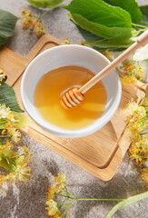 Obraz premium Linden honey in bowl with dipper and flowers
