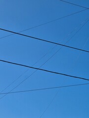 Fototapeta premium Black Power Lines Crossing Clear Blue Sky Background