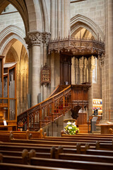 Naklejka premium Gothic Cathedral Interior with Ornate Wooden Pulpit, Pipe Organ and Stone Arches, Geneva Switzerland - A grand interior view of a Gothic cathedral. St. Pierre's Cathedral in Geneva.