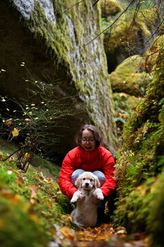 A young woman holding a puppy in the forest