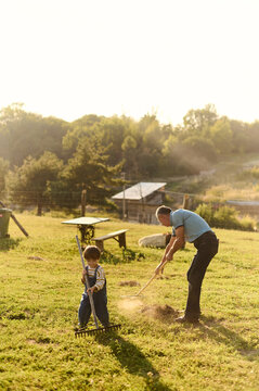 Grandfather and grandson are raking hay