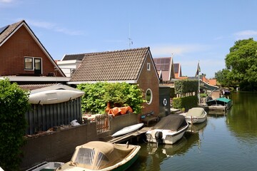 Naklejka premium Brick houses and parked cars create a typical residential street scene in Medemblik, North Holland. The neighborhood reflects everyday Dutch urban life. 