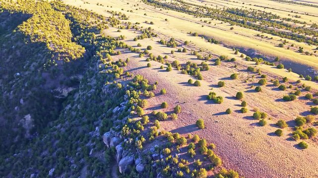 Aerial sunset view of rugged rocky terrain and scattered junipers above Wind River Canyon in Wyoming