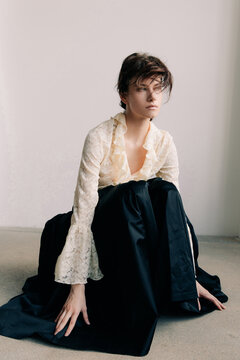 Cinematic fashion portrait with lace blouse and dark drapery