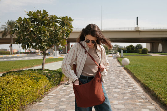 Tourist woman on vacation walking in the street of big green city 