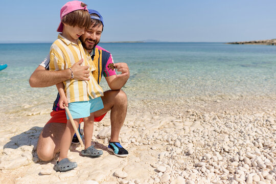 Father and child exploring shells on beach