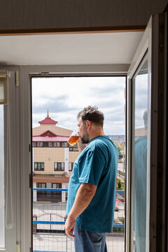 A man with a drink on a balcony