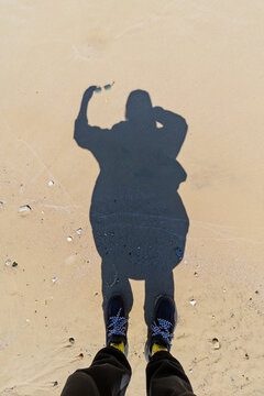 Shadow of a man on a sandy beach.