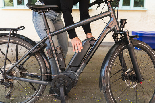 Close-up of hands installing battery on electric bike frame