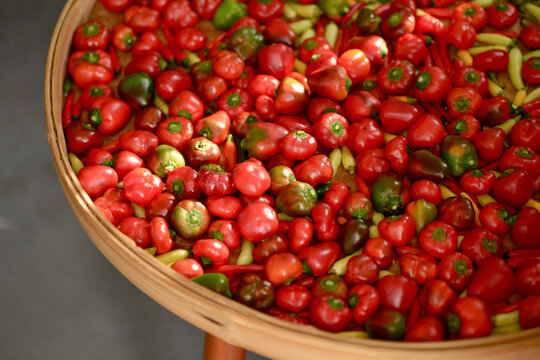 Close-up of fresh small chili peppers in a large woven bamboo basket.