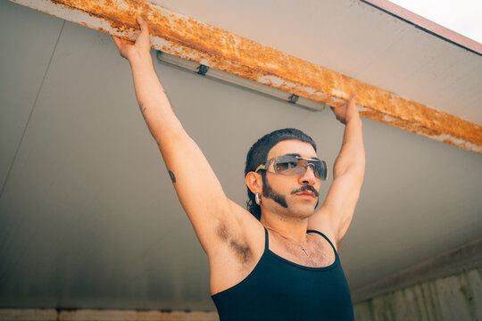 Man Holds on to a Rusty Beam in an Empty Space During Daylight