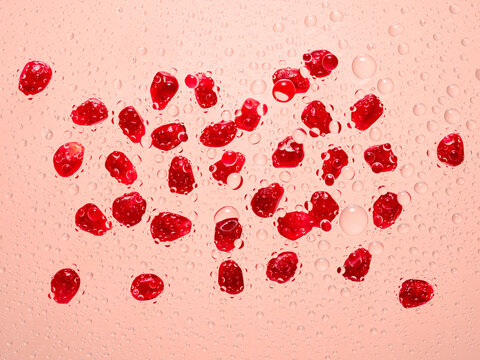 Pomegranate seeds shot though glass with water droplets
