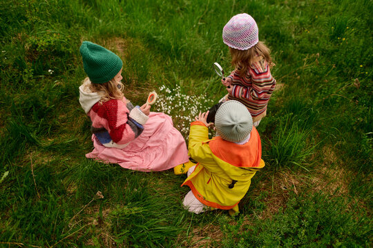 Children Exploring Grass With Magnifying Glasses