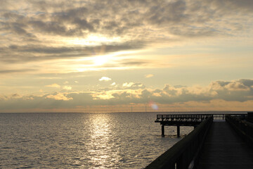 Fototapeta premium Sunset over Öresund with Öresundsbron bridge silhouette and pier at Bjärred