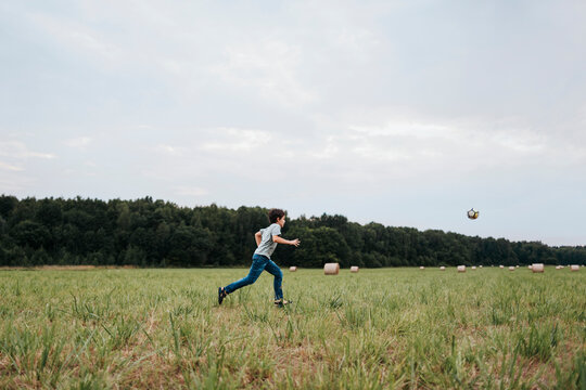 Boy Joyfully Chasing a Soccer Ball in an Open Field