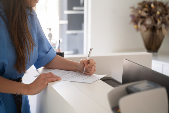 Woman Completing Paperwork at a Reception Desk 