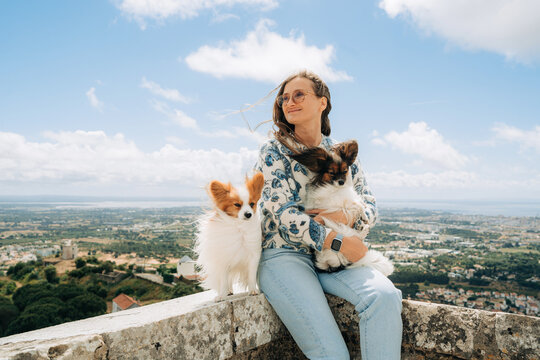 Smiling woman holding small dog while sitting beside another flu