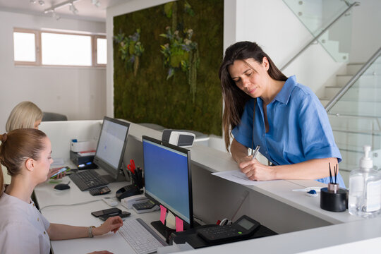 Patient Completing Paperwork at a Reception Desk 