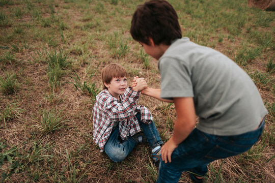 Two Young Boys Engage in a Playful Arm Wrestling Match Outdoors