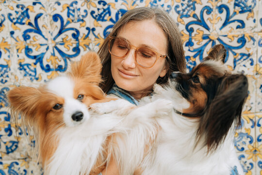 Portrait of a woman with two dogs against tiled wall