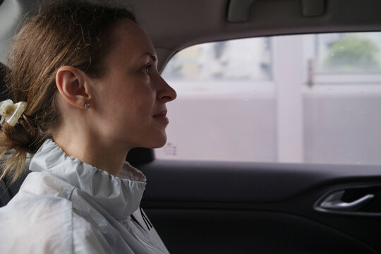 Woman sitting in a car looking outside on a rainy day